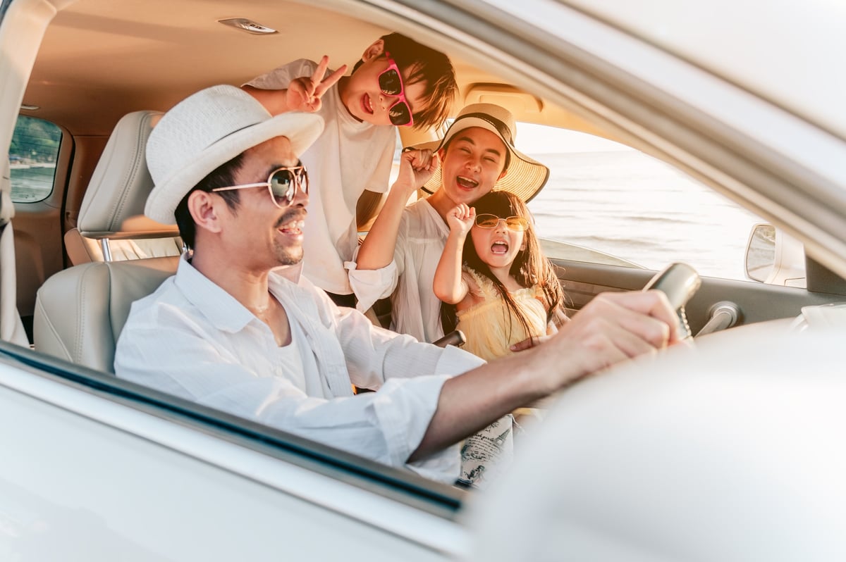 Portrait of family enjoying beach trip with their favorite car