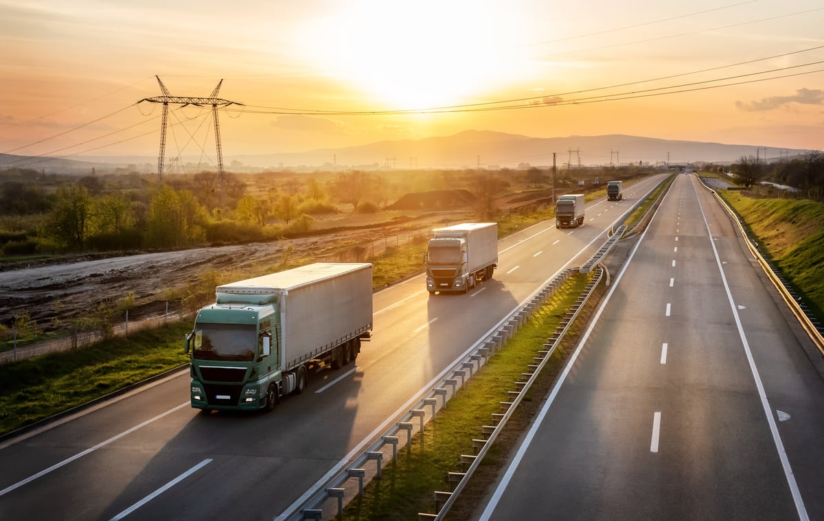 Convoy of green trucks with grey containers on a highway, cargo transportation concept