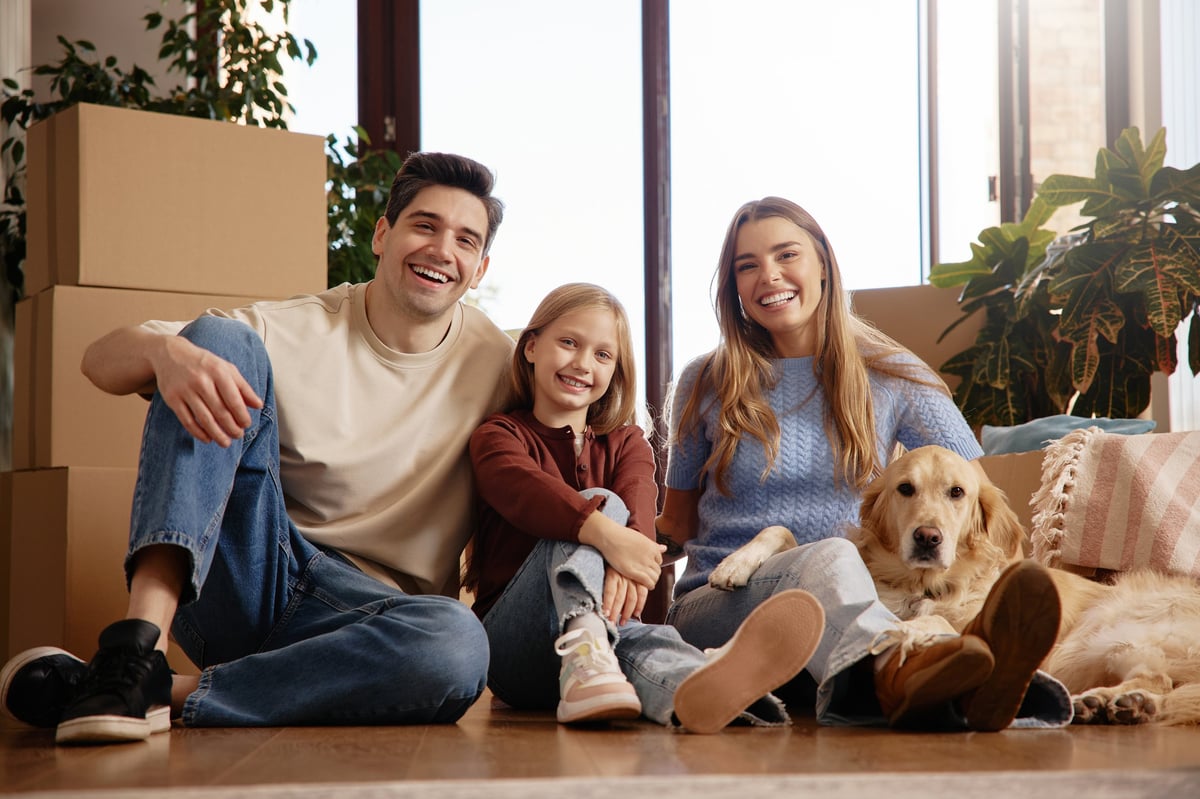 Cheerful family with golden retriever sitting together in their new home